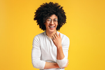 Cute carefree black curly guy laughing on orange background