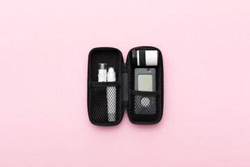Glucometer on a pink background. Device for measuring blood sugar levels. Top view. Space for text.