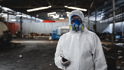 Workers in protective suits inspect chemicals in an old factory, safeguarding against hazards and...