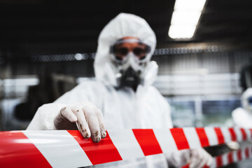 Workers in protective suits inspect chemicals in an old factory, safeguarding against hazards and...