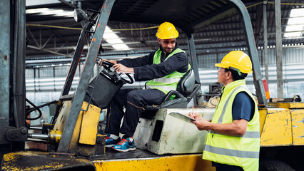 Two men in yellow and green safety vests are standing next to a forklift