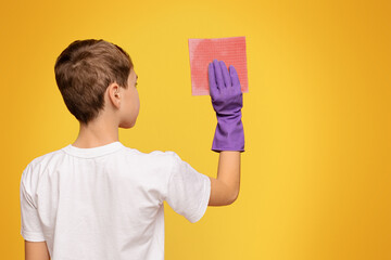 Teen boy washing wall with sponge, back view