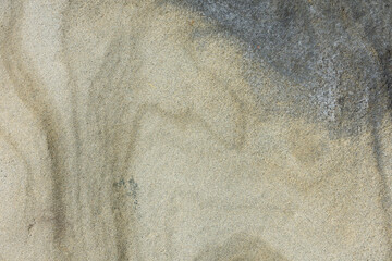 An abstract image of the natural beige and grey colored texture of a slab of sandstone. 