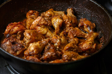 Fried chicken breast pieces in a frying pan in sauce