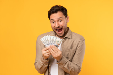 Man Holding Bunch of Money on Yellow Background