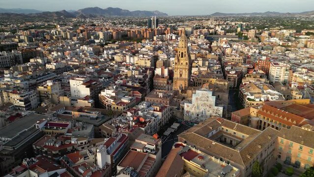 Murcia - Spain, perspective from above. Drone slowly circling above the city center. Cathedral of Murcia and Cardenal Belluga Square. Sunset warm colours. Mountains in background. Travel destination. 