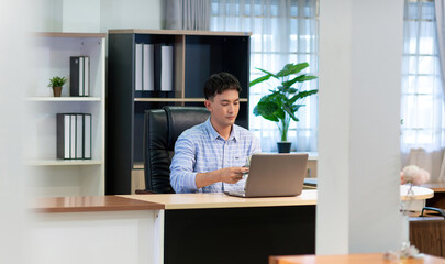 asian business male worker collect money. office treasurer showing arrange cash for company paycheck. spreaded money sheet paper got count by professional success treasurer of business bank on desk