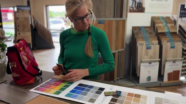 Female interior designer or architect choosing color sample from swatch board in design studio. Floor and wall finishing material for architecture and construction industry.