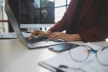 .Cropped image of professional businesswoman working at her office via laptop, young female manager using portable computer device while sitting at modern loft, flare light, work process concept