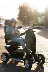 Woman tourist riding a four wheel mobility electric scooter on a city street