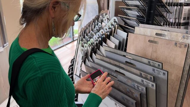 Female interior designer or architect looking at ideas on phone in design studio. Floor and wall finishing material for architecture and construction industry.