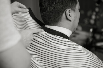 Barber fastens a cape on a client