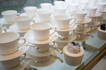 Many white cups and saucers standing on top of each other