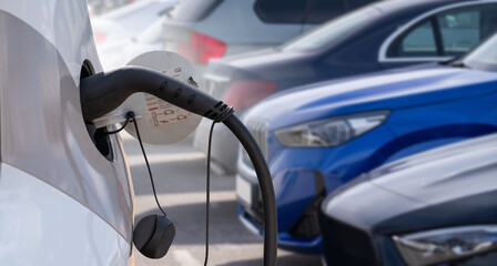 Close-up of a charging electric car on the background of parked cars