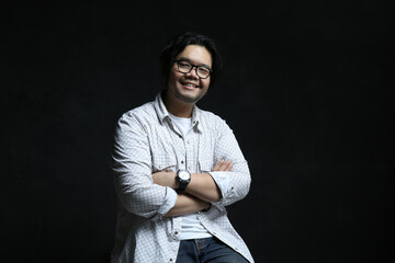 the expression of a friendly smiling man with crossed arms on black background