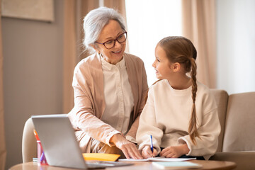 Older Woman and Young Girl Sitting at Table With Laptop