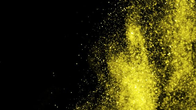 Golden glitter background in slow motion. Beautiful transition with real gold particles flying in wind on black background, shot with depth of field. Gold dust bokeh abstract background