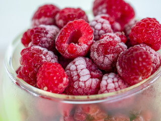 raspberries frozen in a glass dish, side view, visible frost on red fruits
