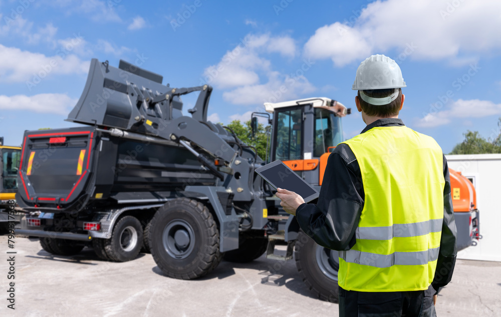 Poster Engineer with a digital tablet on the background of construction machines