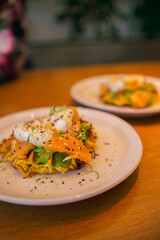 Potato waffle with salmon, poached egg in spinach sauce on white plate.