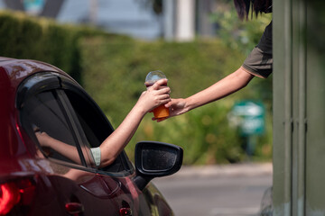 Hand Man in car receiving coffee in drive thru fast food restaurant. Staff serving takeaway order...