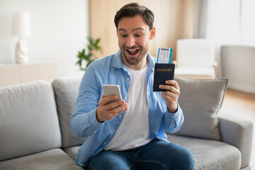 Man Sitting on a Couch Holding Cell Phone and Passport