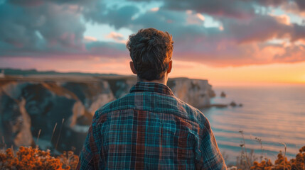 A man is standing on a cliff overlooking the ocean