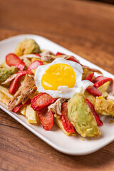 Salchipapa, French fries, hot dog, chicken, egg and crispy avocado.