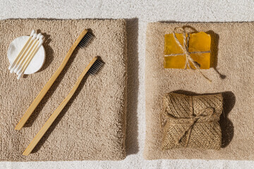 Set of eco cosmetic products and tools. Handmade soap, bamboo toothbrush and ear buds on beige bath towel.