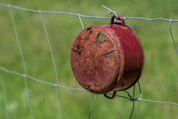 Rustic Charm. The Weathered Pot on the Wire Fence. Green blurry background.