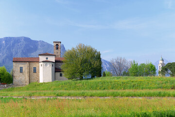 Church of San Giorgio and campanile of the Rosario churh in natural landscape in Annone di Brianza, Italy with mountains and blue sky - obrazy, fototapety, plakaty