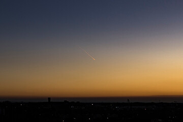 Meteorito cayendo sobre el skyline de la ciudad al atardecer. Cometa entrando en el espacio visible...