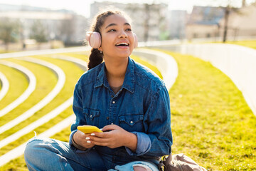 Young Girl Sitting on Grass Listening to Headphones