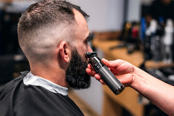 Close-up of a man having his beard trimmed with an electric razor