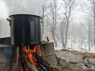 Maple sap boiling in a large pot over a fire to evaporate down into maple syrup