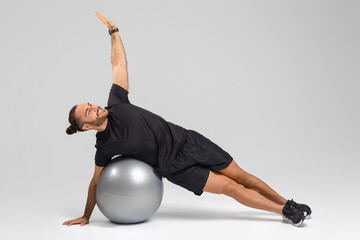 Man Exercising on Exercise Ball On Grey Background