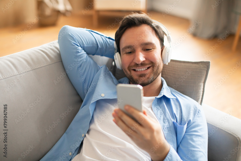 Poster man reclining on couch using cell phone