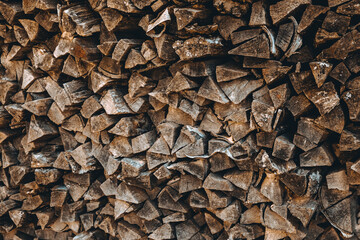 Chopped firewood pile. Woodpile wall. Heap of old dry pine woods. Brown textured background. Natural solid fuel resources. Winter preparation. Countryside pattern. Rustic style details. Woodworking