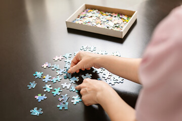 Woman Assembling a Blue and White Jigsaw Puzzle