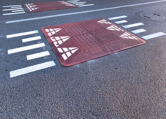 Red speed humps - raised squares made of rubber beveled on the sides installed in the middle of the...