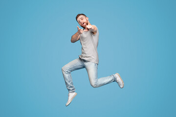 Cheerful man in jumping indicating happily at you