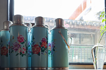 Thermos bottles with Chinese drawings next to a window