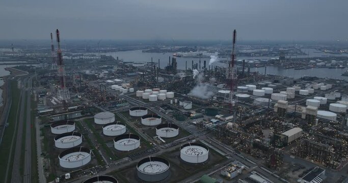 Aerial drone overview view on refinery in the port of Antwerp. Processing of fossil fuels. Petroleum industry at dusk. Heavy industrial installation. Silos containers and smokestacks. Antwerp, Belgium