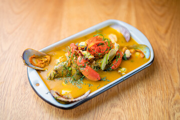 Parhuela or special seafood soup with crab, mussels and cassava, decorated with seaweed and served in a white bowl