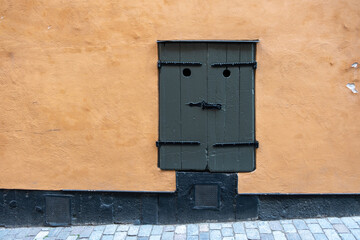 Vintage dark grey closed wooden window with hole and latch looks like a bad face. Stockholm Sweden.
