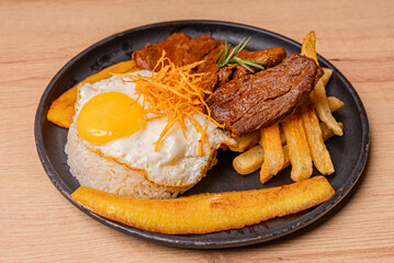 Poor style steak, potatoes and fried plantains, as well as white rice with its egg whipped with the yolk.
