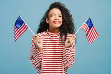 Excited girl, teenager wearing stylish casual clothes holding American flags, rejoicing in victory