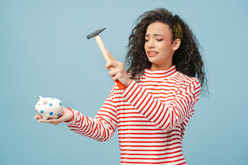 Scared curly hair girl, teenager holding iron and broking piggy bank, isolated