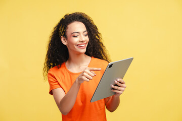 Happy curly haired girl, teenager holding digital tablet, pointing, working online isolated