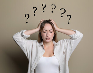 Amnesia. Confused young woman and question marks on beige background